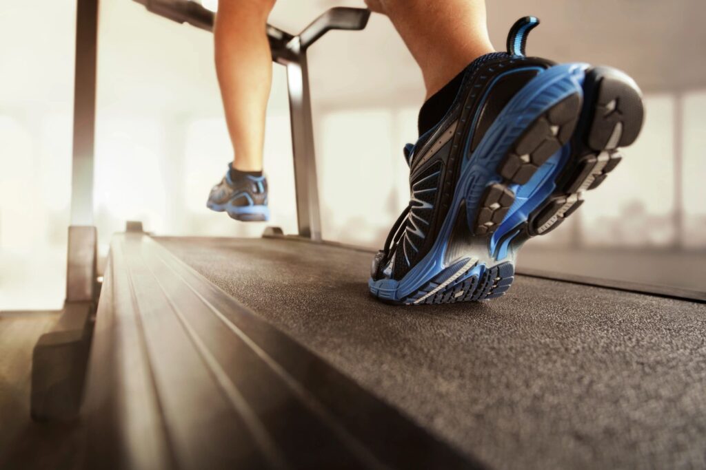 Close-up of a person running on a treadmill in athletic shoes, representing fitness, rehabilitation, and physical therapy services.